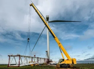 Crawler crane hoisting a load against clear sky