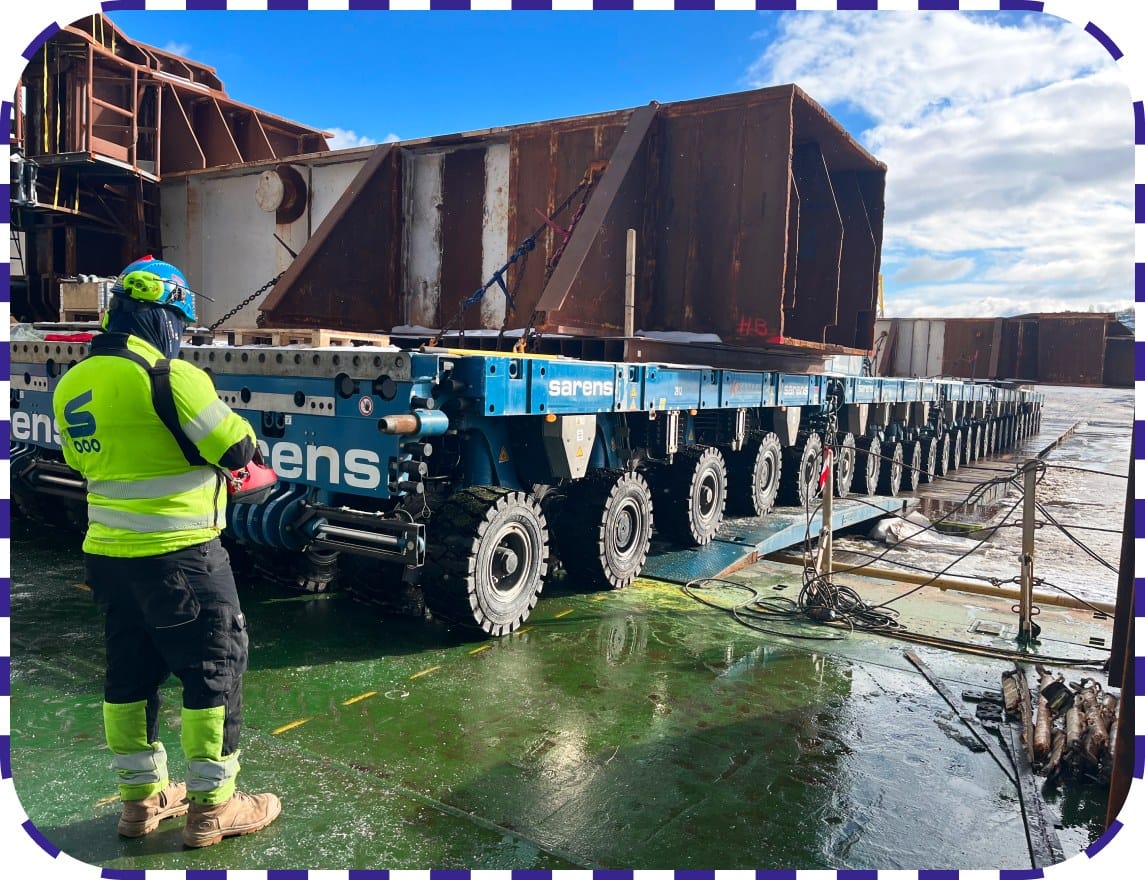 Workers guiding heavy cargo during transport operation