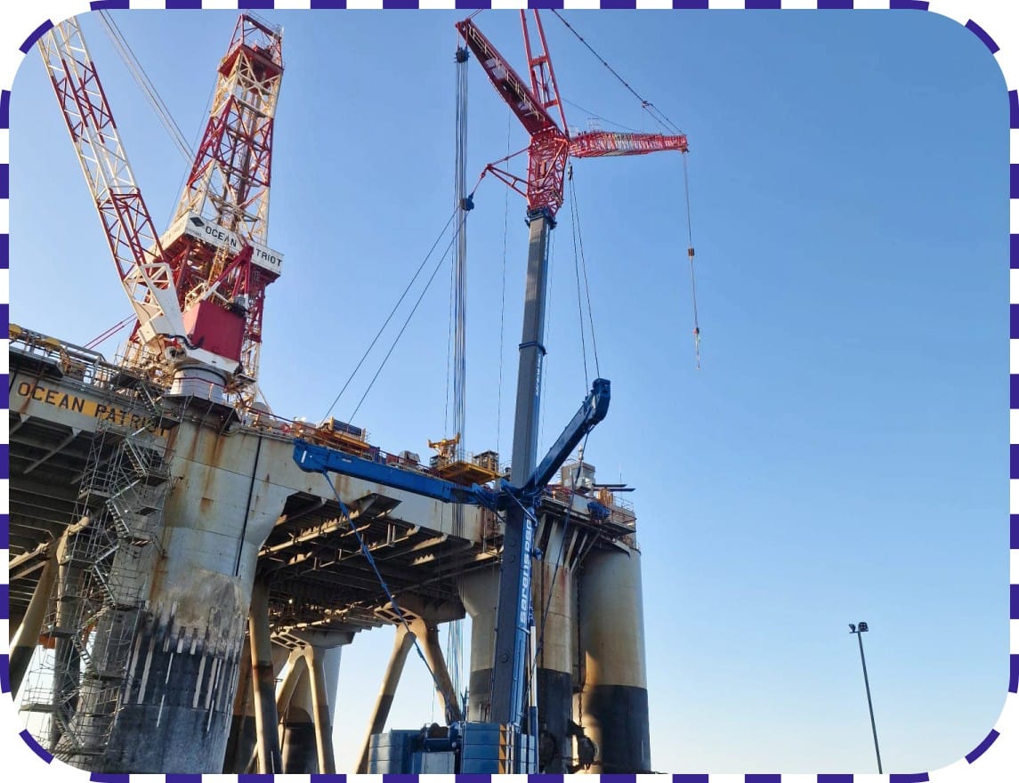 A crane hoists a sizable structure over a bridge