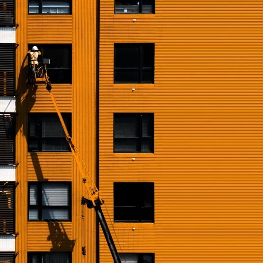 Cherry picker lifting technician beside building for maintenance